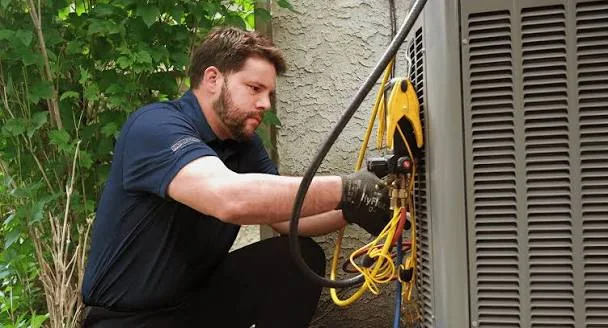 HVAC technician checking gauges on a residential air conditioning condenser