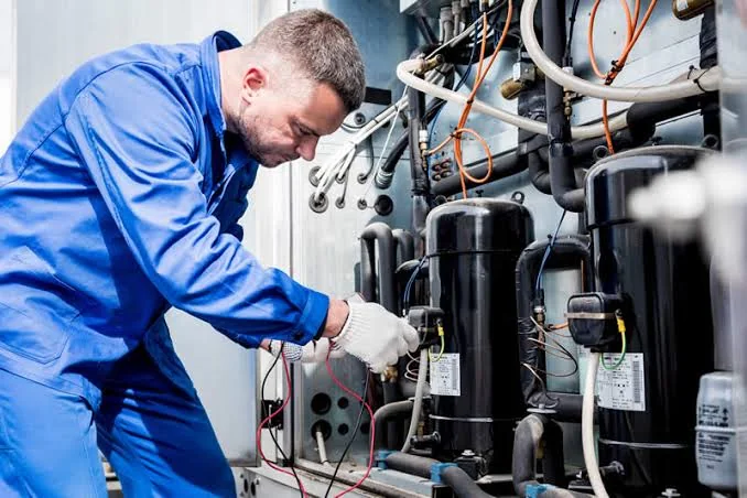 HVAC technician testing electrical components inside mechanical equipment