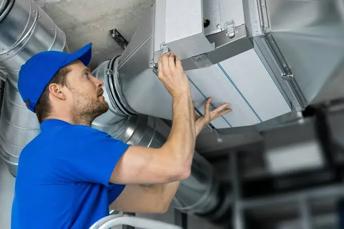 HVAC technician inspecting metal ductwork and airflow equipment