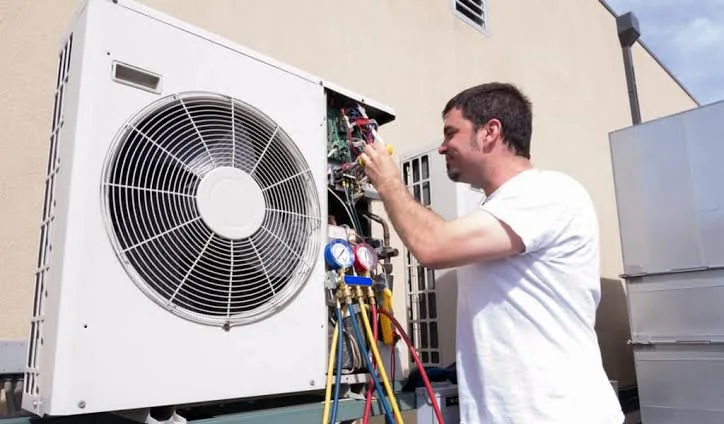Technician servicing the controls of an outdoor heat pump system