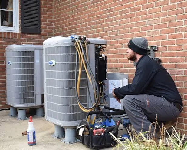 HVAC technician servicing outdoor residential heating and cooling equipment