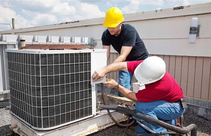 Two technicians working together on a commercial air conditioning unit